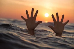 Hands out of sea against sunrise